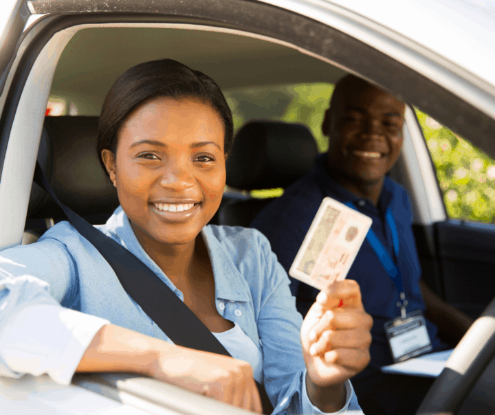 A picture of a lady holding her license during a driving lesson.